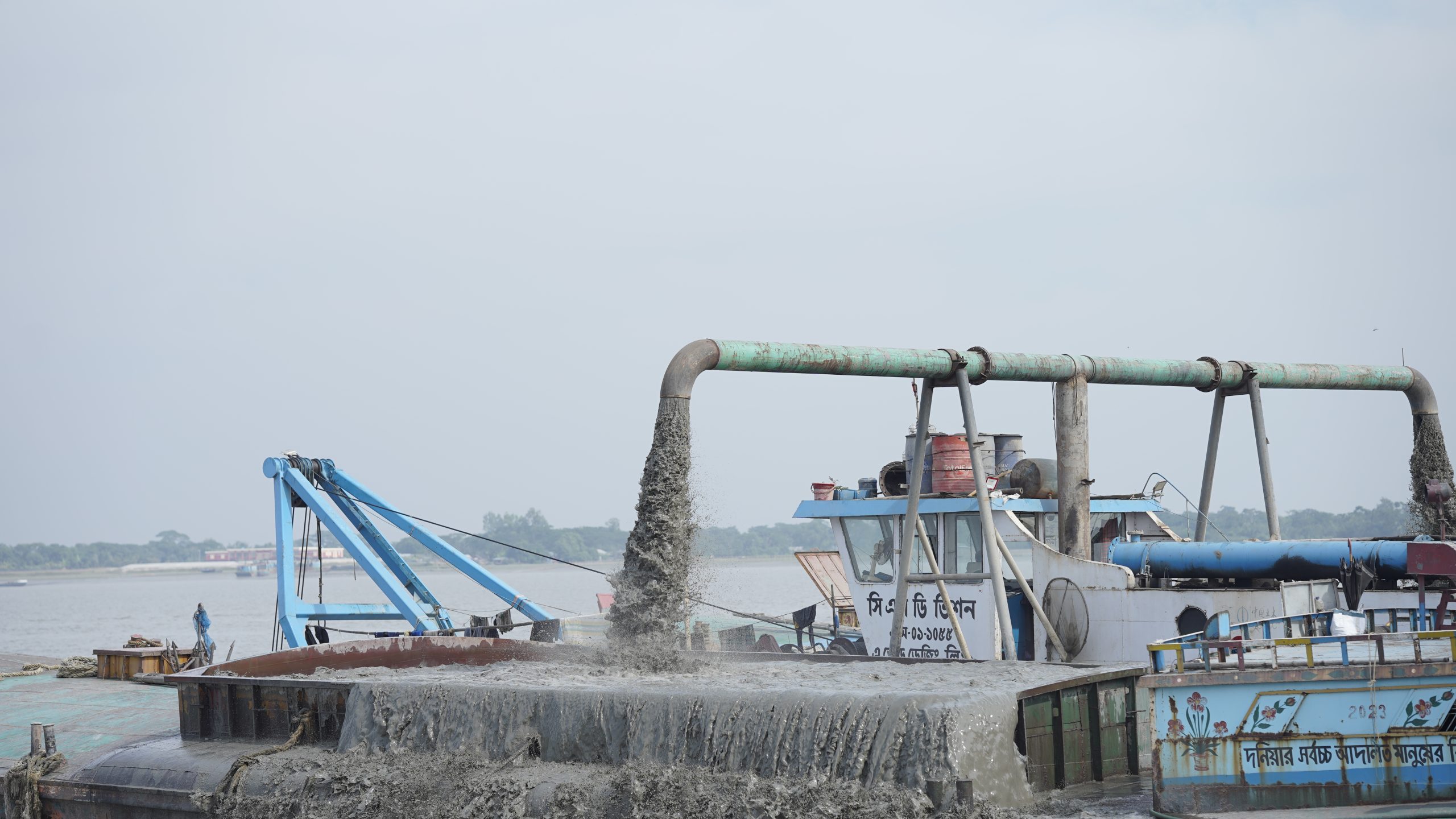 Dredger operating close to a jetty, removing underwater debris for safe vessel docking.